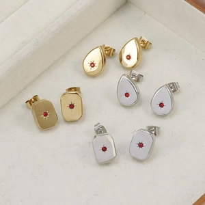 Detailed view of silver and gold earrings with red starburst zircon on beige velvet