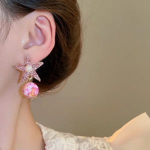 Detailed view of pink star earrings with ceramic beads on a model for jewelry display