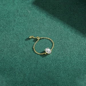 Adjustable gold chain ring with oval cubic zirconia on dark green background