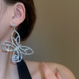 Close-up of sparkling cubic zirconia butterfly drop earrings on a female model
