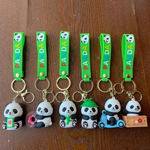 Collection of six cute cartoon panda keychains with silicone wristbands on a wood surface