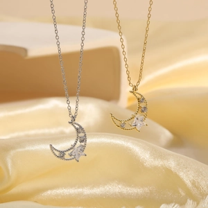 Close-up of gold and silver moon star pendants with zircons on yellow silk background