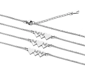 Macro detail of silver stainless steel chain with triple heart pendants and lobster clasp