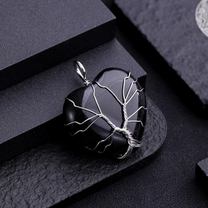 Macro shot of heart-shaped black stone pendant with silver wire tree of life wrap