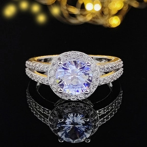 Macro shot of a halo setting engagement ring with a round center stone on black surface