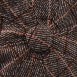 Macro view of plaid octagonal hat featuring wool blend tweed fabric and top button detail
