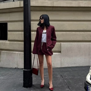 Detail shot of a dark red jacket with collar and zipper pockets on a street model
