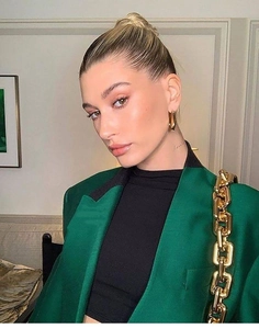 Close-up of golden geometric U-shape earrings worn with a chic green suit and chain strap