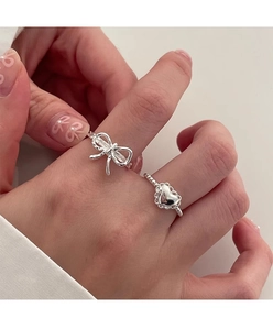 Close-up of s925 silver rings with bow and heart shapes worn on a hand