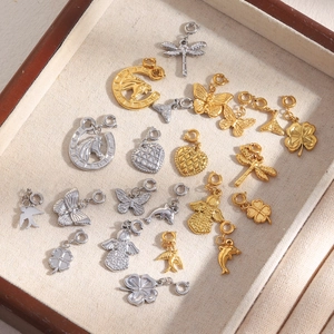 Assorted 18K gold and silver charms including butterfly, angel, and dolphin on a tray