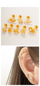 Detailed views of gold titanium studs with zircon including leaf, heart and crown designs