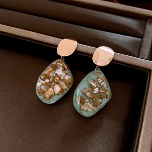 Detail of vintage geometric earrings with green resin pendants and pearl shell inlay