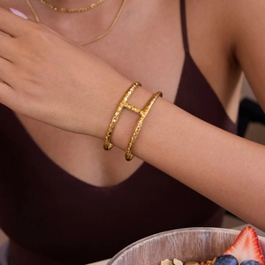 Close-up of a 18K gold-plated stainless steel hammered cuff bracelet on a model wrist