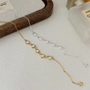 Close-up of gold and silver heart bracelets with white zircon on a textured surface