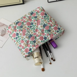 Detailed macro view of floral quilted cotton makeup bag with brushes and cosmetics inside