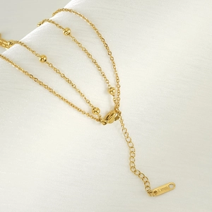 Close-up of gold double-layer necklace showing S.STEEL hallmark and clasp detail