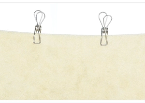 Detail of stainless steel wire clips holding cream fabric showing texture and flat seams