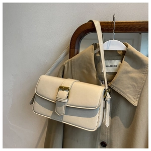 Close-up of beige oil wax leather shoulder bag with vintage metal buckle and slim strap