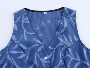 Detail of blue denim jacquard vest with leaf pattern and frayed edges and white button