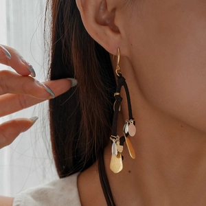 Détail de boucles d'oreilles bohèmes avec pendentifs métalliques dorés et argentés