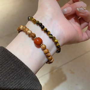 Detail of beaded bracelet with brown tiger eye, yellow rutilated quartz and red agate bead