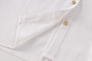 Close-up of white linen shirt showing golden buttons and fine fabric texture details