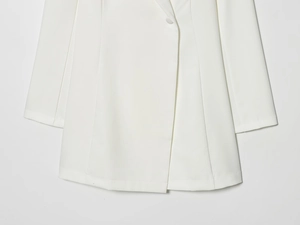 Detail of white blazer dress showing single-button closure and fine stitching quality