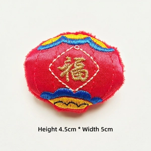 Detail of red satin Fu character embroidery patch with gold thread and blue clouds decor