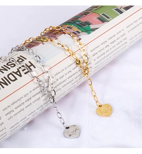 Detail of heart pendants with Love engraving on gold and silver link chains