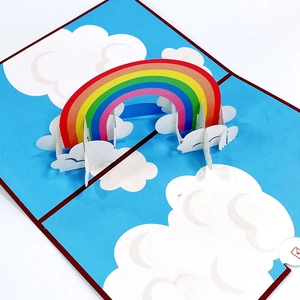 Detailed top view of 3D pop-up birthday card with rainbow and clouds over blue sky