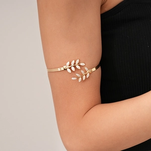 Detail of adjustable gold-tone leaf arm cuff with white enamel inlay on a model