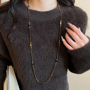 Detailed view of Tiger Eye beaded long necklace styled on a dark sweater for winter look