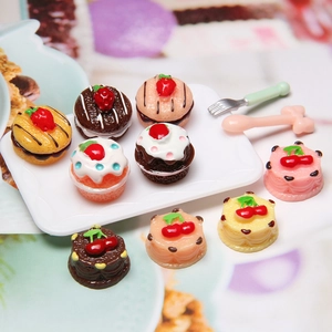 Miniature resin strawberry cupcakes and sliced cakes set on a white display plate