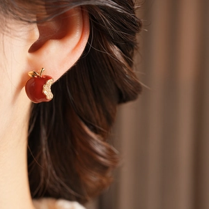 Macro shot of red enamel apple earring with pavé-set zircons on a gold-plated base