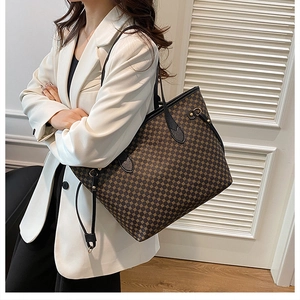 Detail view of large brown geometric pattern tote bag worn with a white blazer