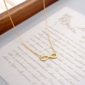 Elegant gold infinity symbol pendant necklace displayed on a minimalist background paper