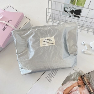 Detailed top view of silver metallic cosmetic bag with crinkled texture on white desk