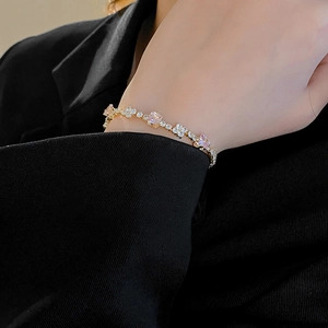 Detail of pink and white zircon stones on a gold-plated bracelet worn on a wrist