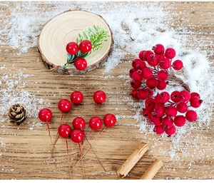 Detailed close-up of artificial red holly berries and frosted branches on a snowy wooden table