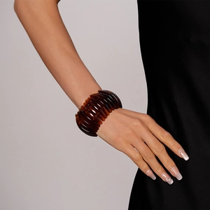 Gros plan d'un large bracelet en résine ambrée à texture nervurée au poignet d'un modèle