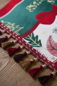 Close-up of Christmas table runner with Merry Christmas embroidery and red gold tassels