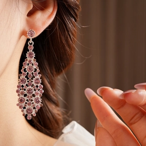 Primer plano de aretes colgantes geométricos de circón rosa con pasador de plata en una modelo