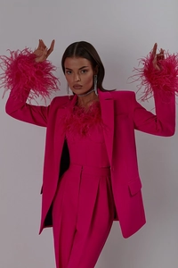 Detail of ostrich feather cuffs on a vibrant fuchsia blazer and high-waisted pants suit