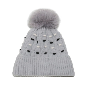 Detalle del tejido de punto acanalado y pompón de pelo sintético en el gorro gris