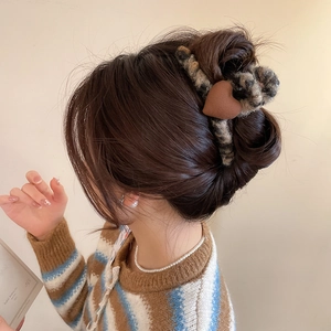 Détail de la pince à cheveux en peluche léopard avec cœur brun portée par un mannequin
