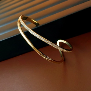Detail of gold-plated minimalist open bangle with shimmering cubic zirconia stones