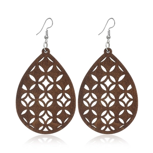 Détail de boucles d'oreilles en bois marron en forme de goutte avec motifs géométriques creux