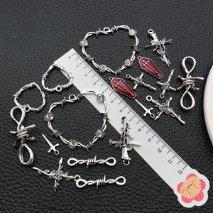 Detailansicht der silbernen Anhänger mit Kreuz und Herz neben einem Lineal auf Leder