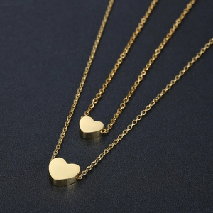 Macro view of gold double-layered heart pendants with fine necklace chain details