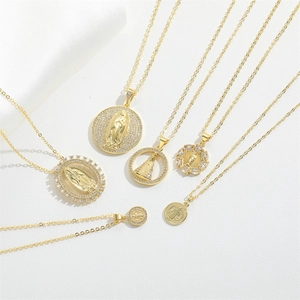 Macro detail of gold plated Virgin Mary and St. Benedict religious pendant necklaces